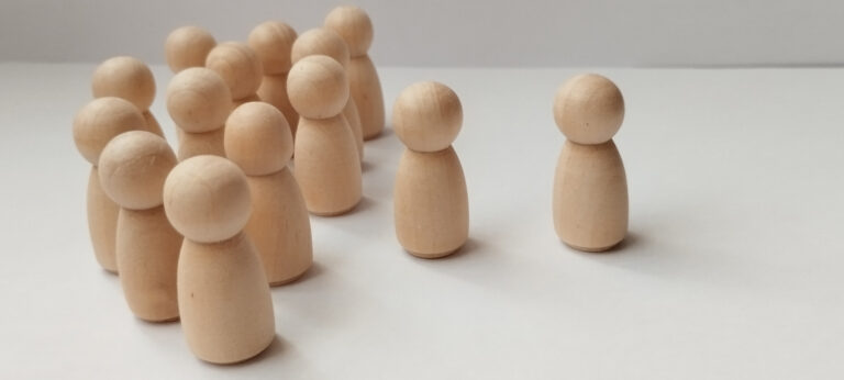 Group dynamics social interaction of wooden figurines minimalist studio photography neutral background close-up conceptual exploration
